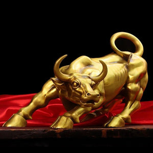 Sculpture de taureau Wall Street en cuivre doré sur fond sombre avec tissu rouge