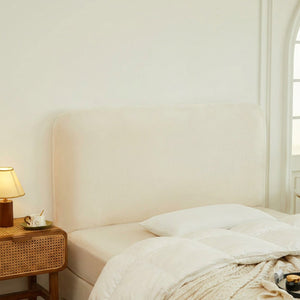 Housse de tête de lit blanche en velours installée dans une chambre lumineuse