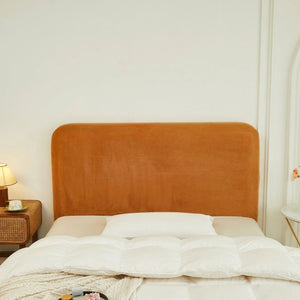 Housse de tête de lit orange en velours installée dans une chambre chaleureuse