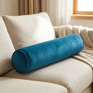 Traversin cylindrique en velours bleu sur un canapé beige