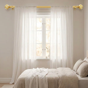Tringle à rideaux dorée dans une chambre avec voilages blancs et embouts boule feuille d'or