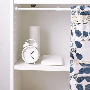 Tringle extensible blanche posée dans une armoire avec un rideau à motif feuilles