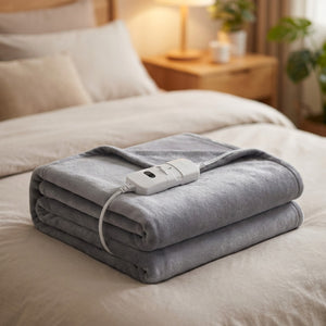 Couverture chauffante électrique grise unie pliée avec son boîtier de commande sur un lit