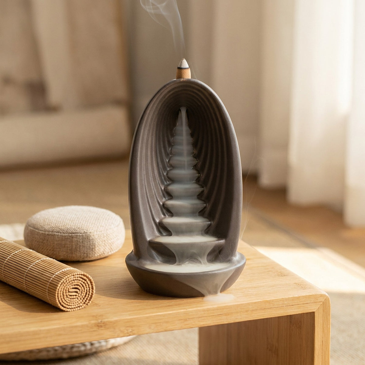 Brûleur d'encens à reflux posé sur une table de méditation en bois avec tapis en bambou et coussin