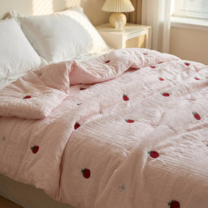 Couette d'été rose brodée de framboises sur un lit doux