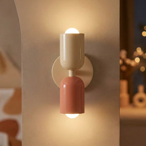 Applique murale LED double tête beige et rose allumée sur un mur clair