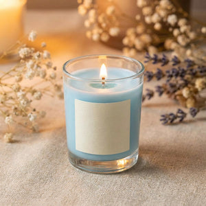 Bougie parfumée bleue en cire de soja allumée sur une nappe en lin