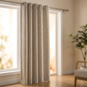 Rideau tamisant beige suspendu à œillets devant une fenêtre