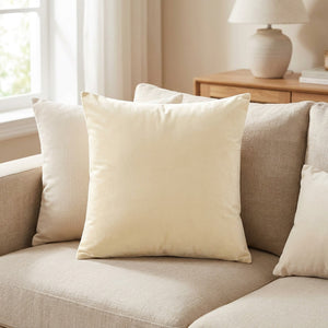 Housse de coussin en velours beige posée sur un canapé en lin clair