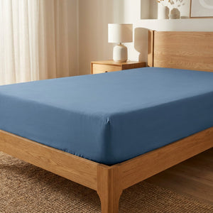 Drap-housse bleu foncé extensible sur un lit en bois dans une chambre moderne