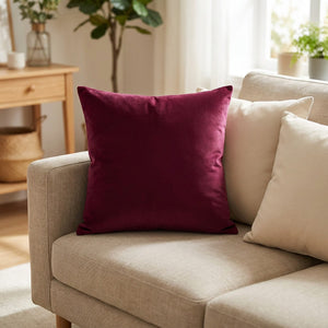 Housse de coussin en velours bordeaux posée sur un canapé en lin clair