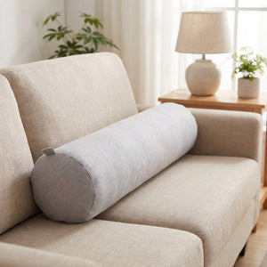 Housse de traversin cylindrique gris clair sur un canapé en lin beige