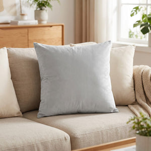 Housse de coussin en velours gris clair posée sur un canapé en lin clair