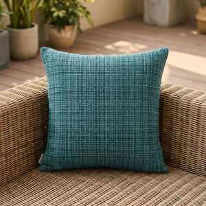 Housse de coussin d'extérieur imperméable turquoise au tissage texturé sur un canapé en rotin