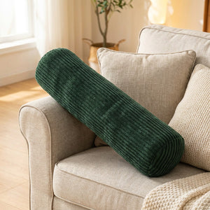 Traversin cylindrique en velours côtelé vert foncé sur un canapé beige