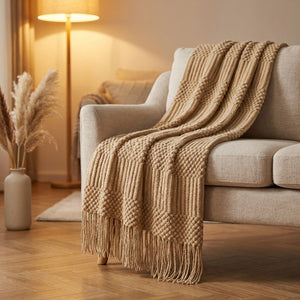 Plaid tricoté beige à franges drapé sur un fauteuil