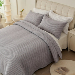 Couvre-lit matelassé gris à fines lignes matelassées installé sur un lit fait