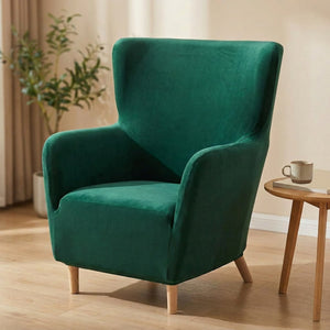 Housse de fauteuil à oreilles en velours vert émeraude installée sur un fauteuil dans un salon lumineux
