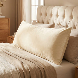 Housse de coussin en velours beige vue de face sur un lit