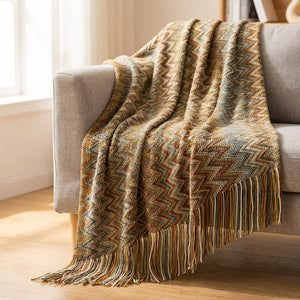 Plaid tricoté chevrons coloris doré drapé sur un fauteuil gris