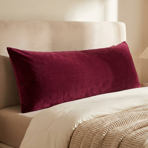 Housse de coussin en velours grenat vue de face sur un lit