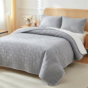 Couvre-lit matelassé tressé gris sur un lit avec deux taies d'oreiller assorties