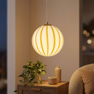 Suspension boule en verre blanc rayée de jaune allumée dans un salon chaleureux