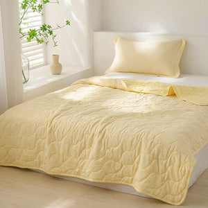 Couette d'été matelassée jaune uni installée sur un lit