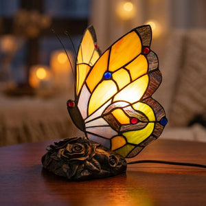 Lampe style Tiffany papillon en vitrail jaune allumée sur une surface en bois