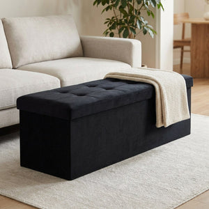 Banc coffre de rangement pliable en velours noir capitonné dans un salon