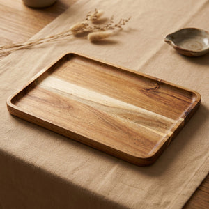 Plateau rectangulaire en bois d'acacia posé sur une nappe en lin beige