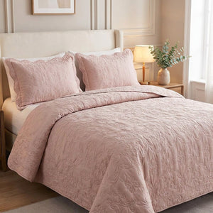 Couvre-lit matelassé rose poudré avec deux taies assorties sur un lit