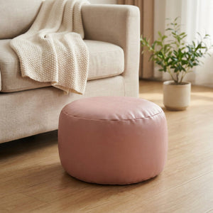 Pouf marocain rond en simili cuir rose près d'un canapé beige