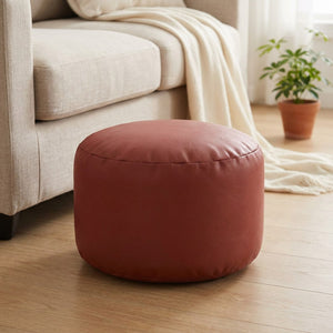 Pouf marocain rond en simili cuir terracotta devant un canapé clair
