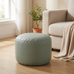 Pouf marocain rond en simili cuir vert sauge près d'un canapé en lin