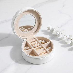 Coffret à bijoux de voyage blanche ouvert sur marbre avec eucalyptus