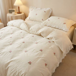 Parure de lit brodée de roses coloris blanche gros plan sur le lit