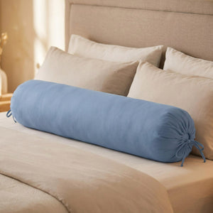 Traversin cylindrique bleu posé sur un lit contre une tête de lit