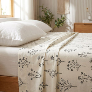 Drap plat en coton motif herbier posé sur un lit dans une chambre lumineuse