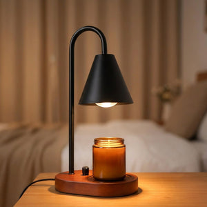 Chauffe-bougie électrique noir allumé sur une table de chevet en bois