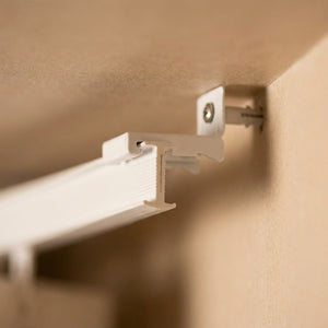 Fixation laterale du rail de rideau vissee dans un angle de plafond