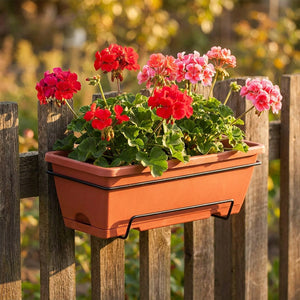 Jardinière de balcon suspendue coloris terracota avec géraniums sur clôture