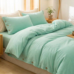 Housse de couette turquoise en coton avec boutons en bois posée sur un lit