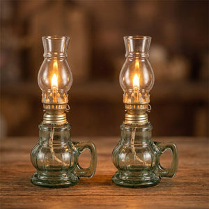 Deux lampes à pétrole en verre teinté vert allumées côte à côte