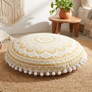 Housse de coussin ronde motif mandala doré posée sur un tapis bohème