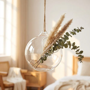 Vase boule en verre transparent suspendu avec pampas et eucalyptus dans une chambre scandinave