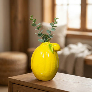 Vase citron jaune sur une console avec des branches d'eucalyptus