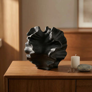 Vase corail noir mat sur buffet nordique avec bougie et galet