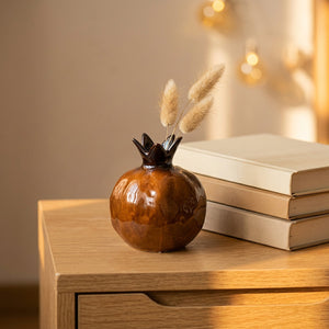 Vase grenade en céramique marron sur une table en bois avec branches séchées