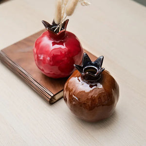 Vases grenades en céramique rouge et marron sur une table avec pampa